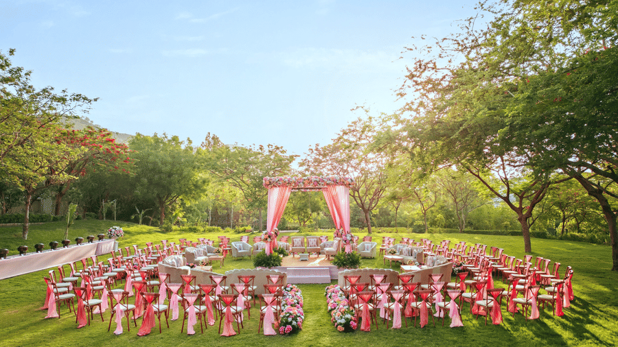 An elegant setting of chairs facing towards the stage in a lawn on a sunny day at Essentia Luxury Resort & Spa, Udaipur
