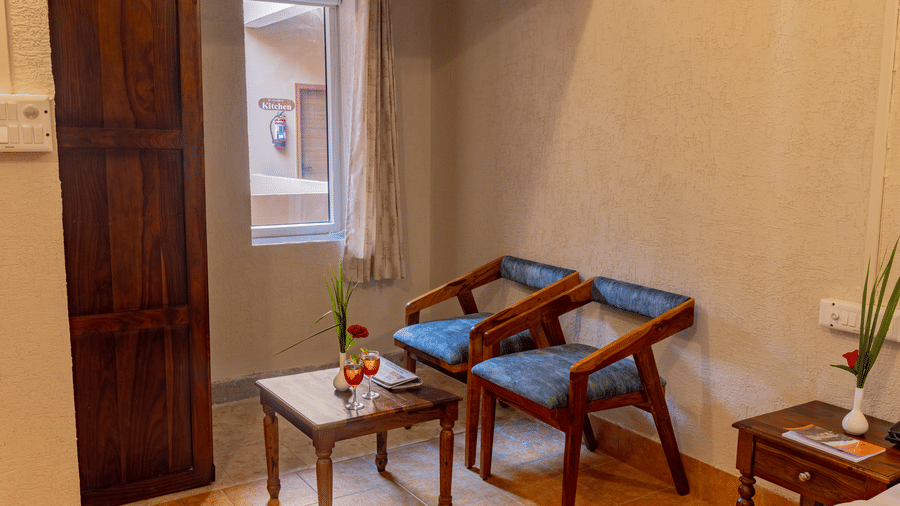A seating area at Estherea Bagh, Ranthambore, featuring 2 upholstered armchairs and a small wooden table.