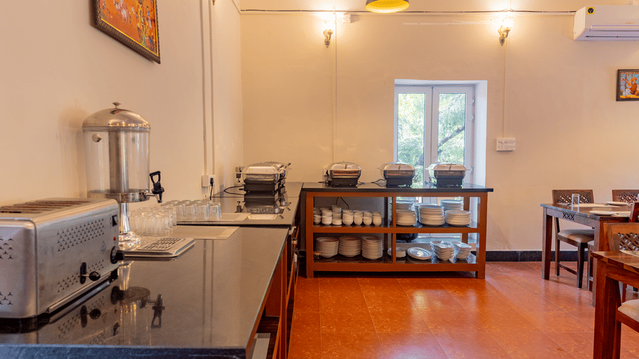 Buffet area at Estherea Bagh, Ranthambore, with a black counter, water dispenser, and shelving for dishes and cookware.