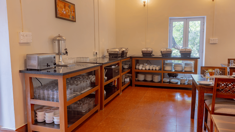 Corner of the dining area at Estherea Bagh, Ranthambore, showing a buffet station with various serving containers and a water jug.