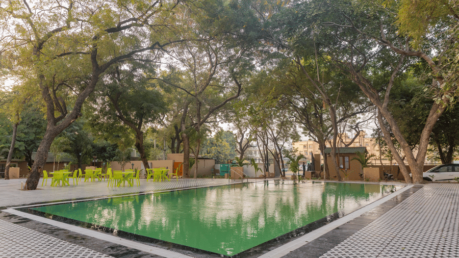 A large outdoor swimming pool at Estherea Bagh, Ranthambore, surrounded by trees and guest cottages.