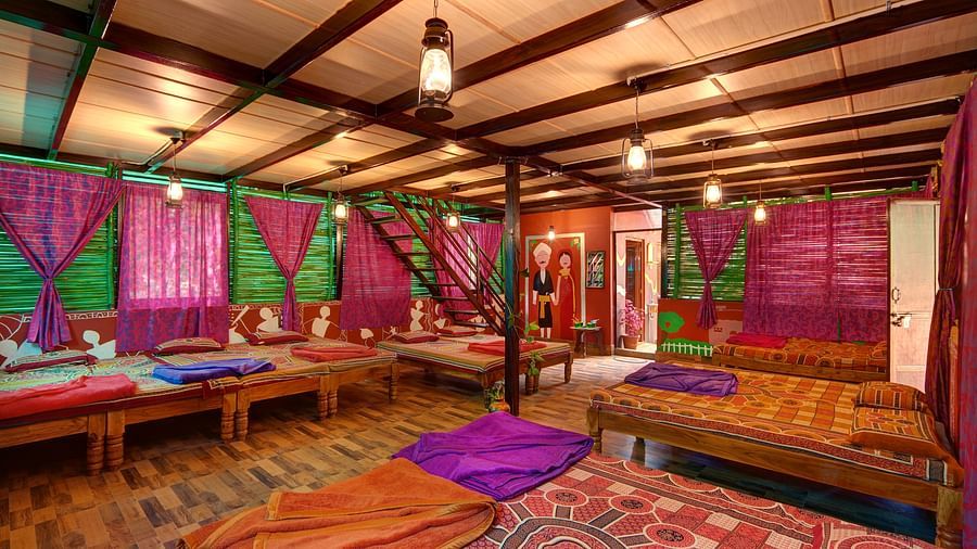 A view of wooden cottage with lanterns hanging from the ceiling, comfortable beds and interesting design on walls - Evergreen County