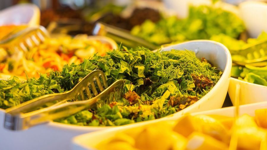 Salad bar with bowls of fresh greens on a buffet counter at Fireflies Resorts, Kabini.