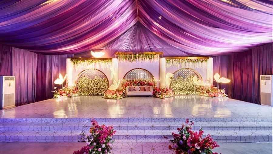 Flowery decorated stage with glowing purple roof and centrepieces along the isle at Grande Bay Resort & Spa.