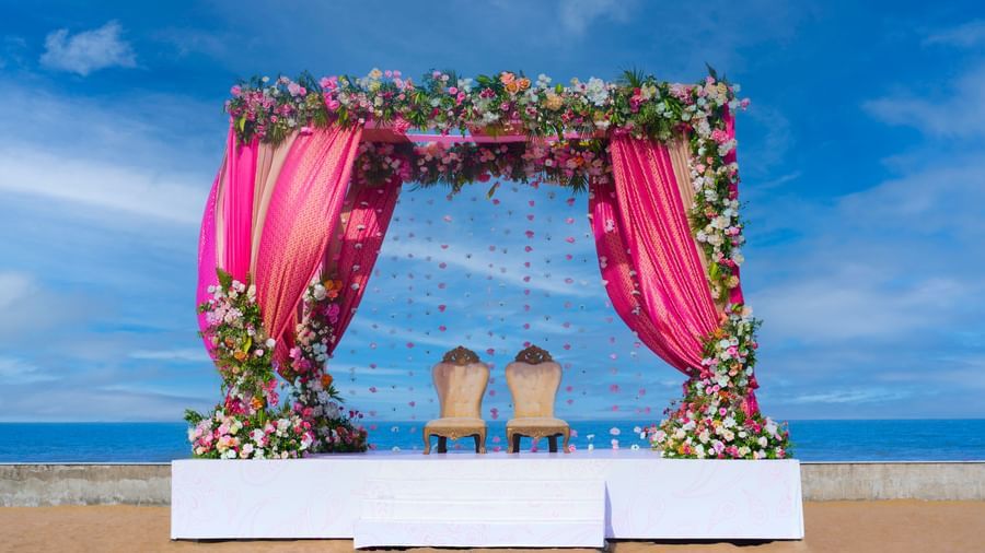 An outdoor platform stage with two chairs under the decorated patio with flowers  featuring the blue sky & sea at the backdrop at Grande Bay Resort & Spa.