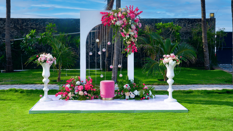 White arch backdrop adorned with fresh flowers on a manicured lawn - Grande Bay Resort & Spa, Mamallapuram