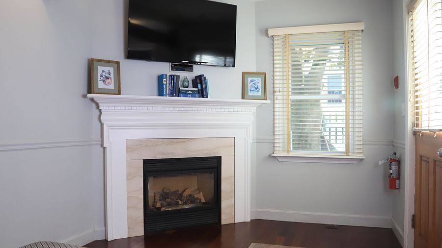 Room with a fireplace, TV, and window at Hartstone Inn.
