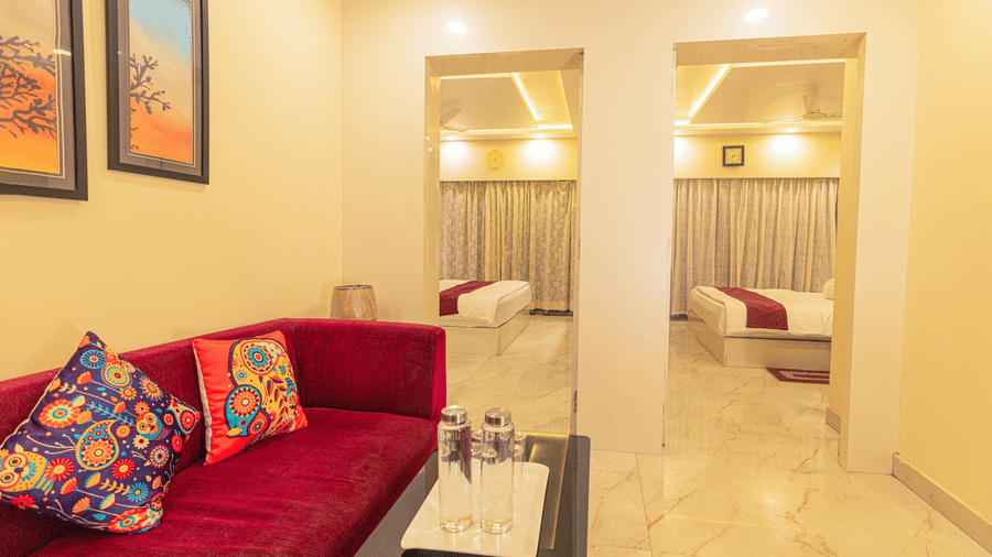 A suite at Hotel Seagull Digha featuring a living area with a sofa and table, and 2 beds in separate rooms visible through open doorways.