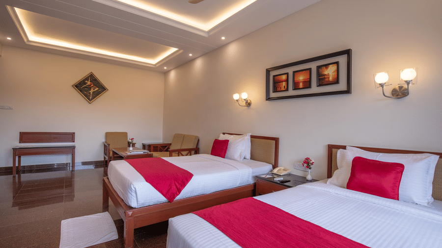A spacious guest room featuring 2 single beds with white linens and red runners - Jenneys Residency, Coimbatore