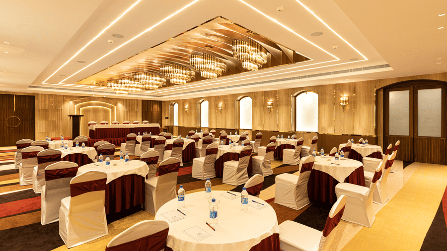 The Ruby hall configured with round banquet tables and maroon-accented chairs for a private event - Jenneys Residency, Coimbatore