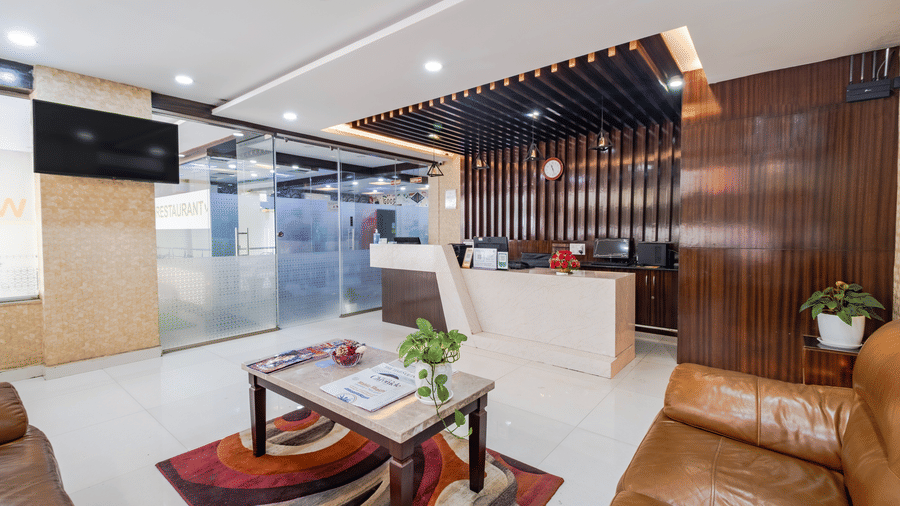 A reception desk, leather sofas, a coffee table, and a small rug are arranged inside the reception lobby at Lemonridge by Monday Hotels - Kukatpally.