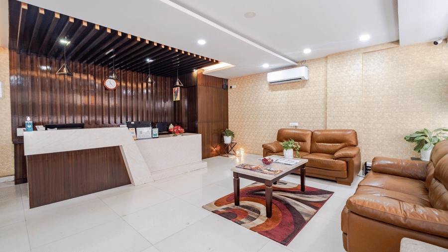 A bright reception lobby at Lemonridge by Monday Hotels - Kukatpally displays a long wooden desk, leather sofas, coffee tables, and indoor lighting