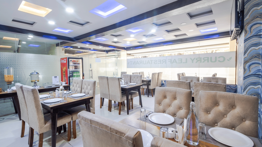 Dining tables arranged neatly in the restaurant Curry Leaf at Lemonridge by Monday Hotels - Kukatpally.