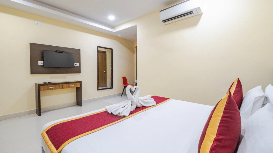 A room featuring a large bed with wall-mounted TV, mirror, and A/C at Lemonridge by Monday Hotels - Kukatpally.