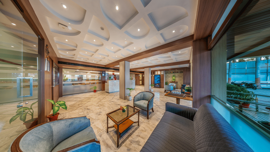 A hotel lobby area of Lords Eco Inn with modern, curved sofas and a wooden ceiling design.