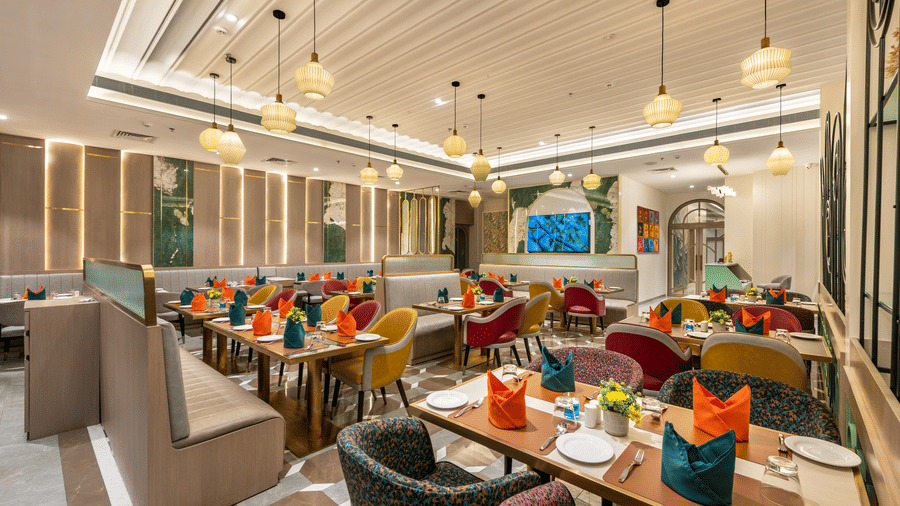 Restaurant dining hall with colorful table settings and stylish pendant lighting at Lords Inn Somnath, offering a vibrant dining experience.