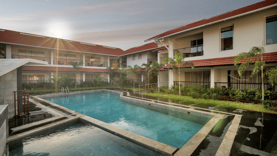 Swimming pool in the courtyard at Mango Hill, Velankanni with buildings and plants.