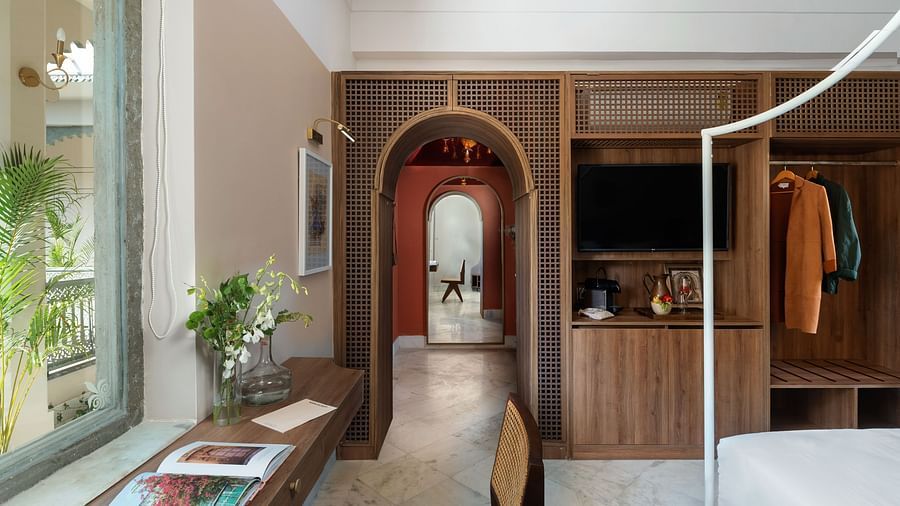 a double bed with a study table next to it inside one of the rooms - Manuscript - Jhilwara Haveli, Udaipur