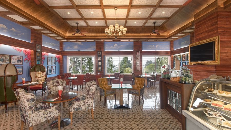 the indoor seating space at the coffee shop with a counter showcasing fresh bakes on the right - Mayfair Himalayan Spa Resort Kalimpong