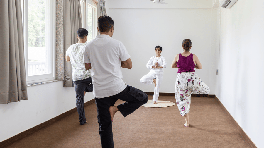 Several individuals are participating in an indoor yoga class together at Megha Resort & Villas, Dehradun.
