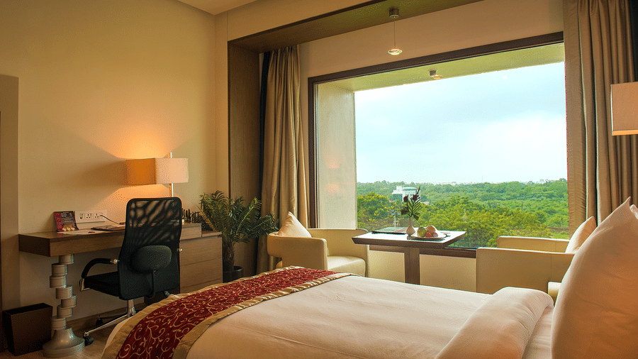 Hotel bedroom with large window, desk, and scenic outdoor view - Narayani Heights Hotel & Resorts