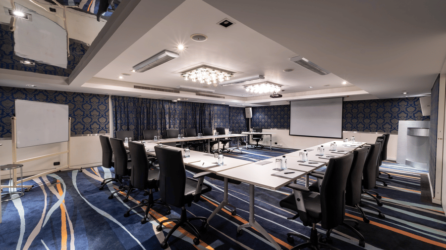 An overview of the Haute Couture conference room, Bangkok, with a projector, a u-shaped table, and executive chairs in view | Night Hotel Bangkok
