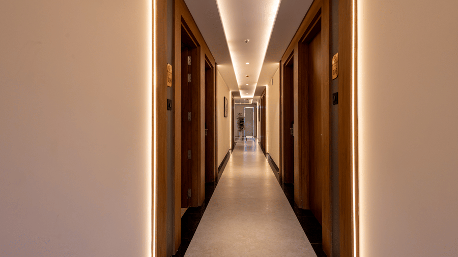 A well-lit, long corridor leading to rooms at Pravasa Stay Bapat Square, Indore.