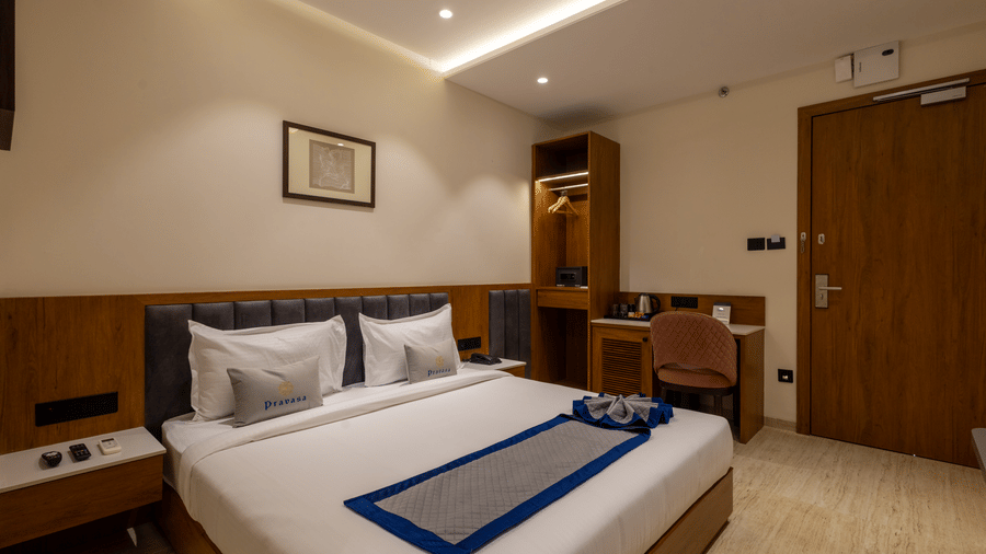 A guest room featuring a bed, television, and work desk at Pravasa Stay Bapat Square, Indore.