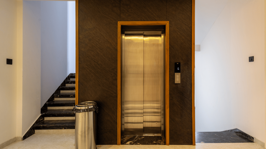 The entrance to the lift, featuring minimalist decor at Pravasa Stay Bapat Square, Indore.