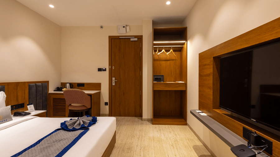 Modern guest room with mounted TV, wardrobe, and cozy bedding at Pravasa Stay Bapat Square, Indore.