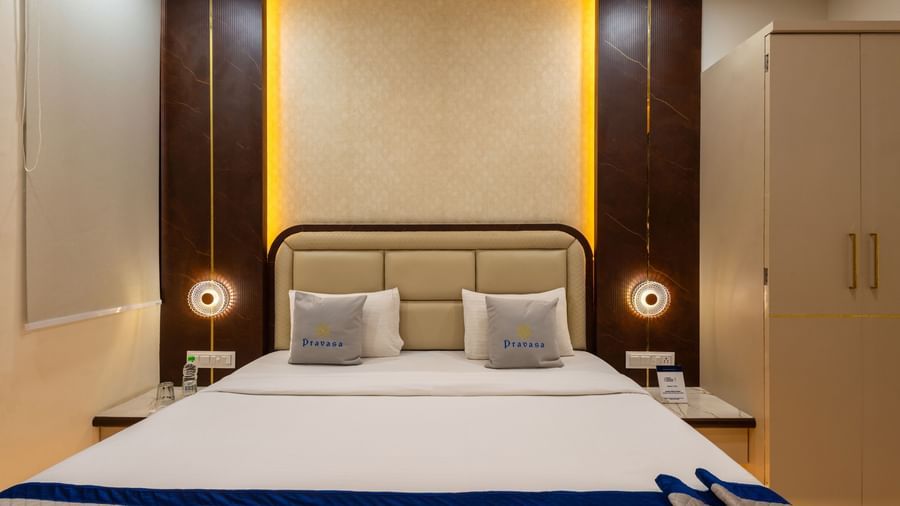 A double bed with headboard, side lamps, and wardrobe at Pravasa Stay Dewas Naka, Indore.