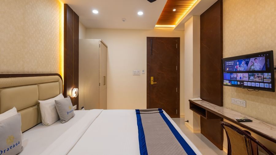 Bedroom with a doublebed, a TV, a chair, ceiling fan, and warm lighting at Pravasa Stay Dewas Naka, Indore.