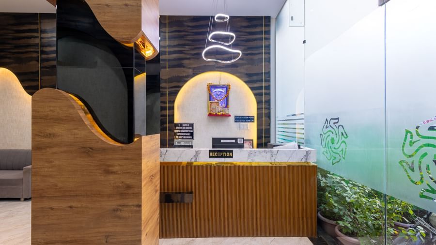 Reception desk with wall art, hanging lights and glass entrance at Pravasa Stay Dewas Naka, Indore.