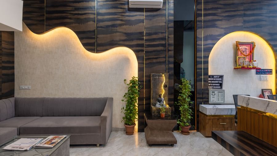 Lobby area with grey sofas, reception desk, and indoor plants at Pravasa Stay Dewas Naka, Indore.