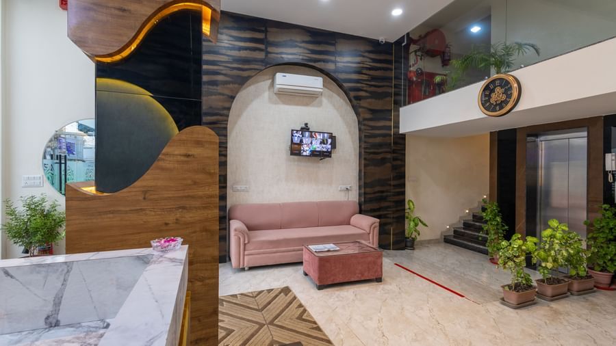 Lobby with sofas, plants, and wall-mounted TV on an arched wall at Pravasa Stay Dewas Naka, Indore.