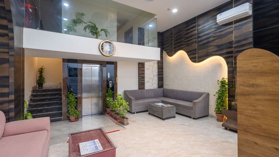 Spacious lobby with sofas, potted plants, and decorative wall panels at Pravasa Stay Dewas Naka, Indore.
