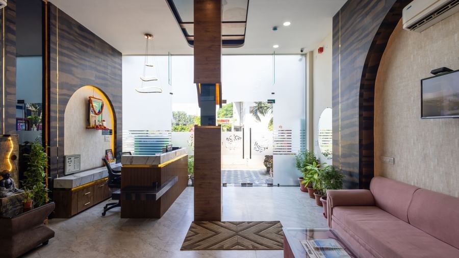 Reception area with sofas, glass entrance, and wooden pillar at Pravasa Stay Dewas Naka, Indore.