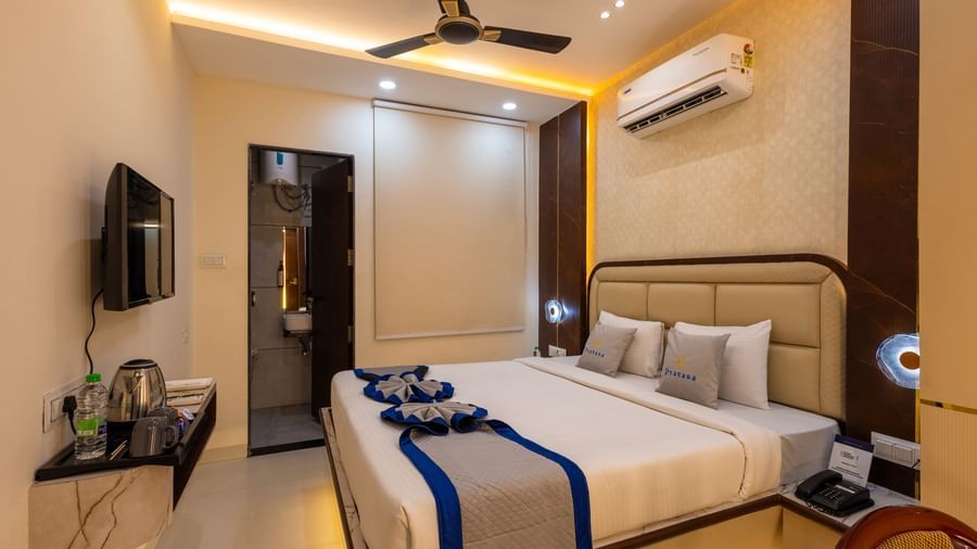 A room with a double bed, TV, ceiling fan, a mirror and wardrobe at Pravasa Stay Dewas Naka, Indore.
