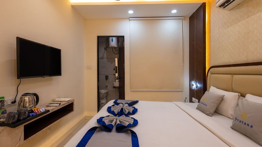 A room with a double bed, TV, a kettle, and dressing area at Pravasa Stay Dewas Naka, Indore.