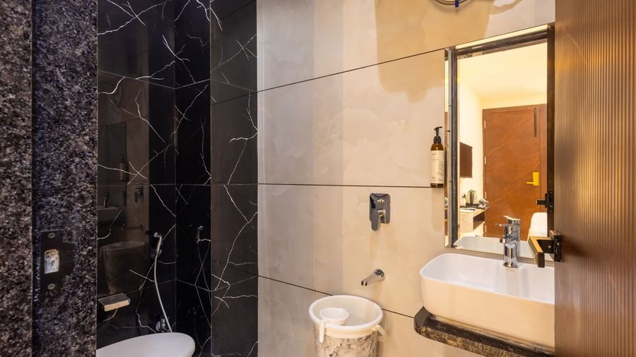 Bathroom with a toilet, washbasin, and black tiled section at Pravasa Stay Dewas Naka, Indore.