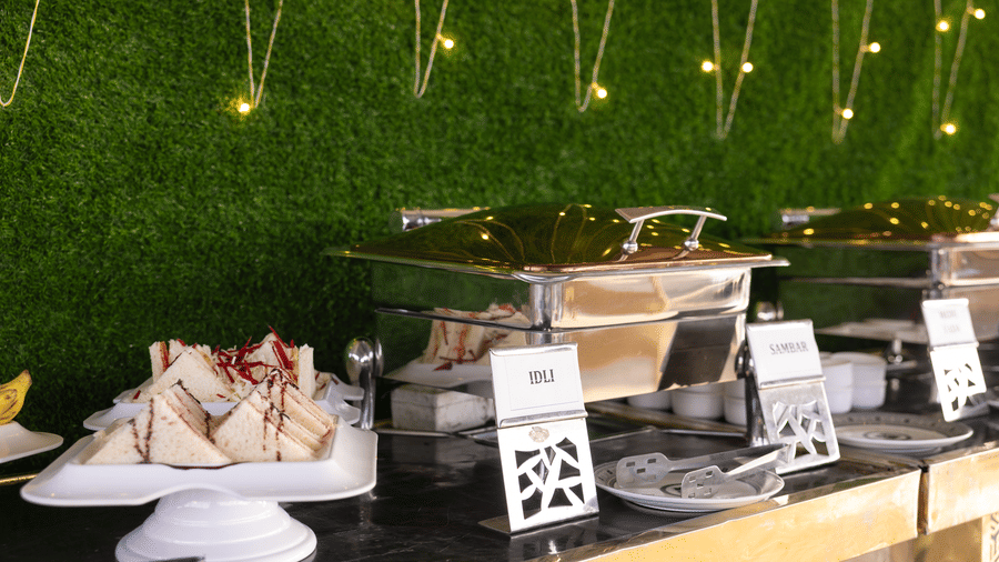 Shot of a buffet setup with food items and a decorative wall background at Pravasa Stay Luv Kush, Indore.