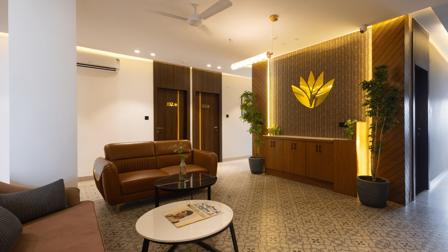 Interior view of the lobby area with a brown sofa and a decorative logo on the wall at Pravasa Stay Luv Kush, Indore.