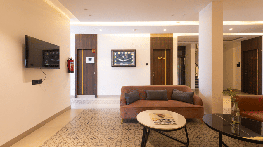 Interior view of the lobby area with seating and a television on the wall at Pravasa Stay Luv Kush, Indore.