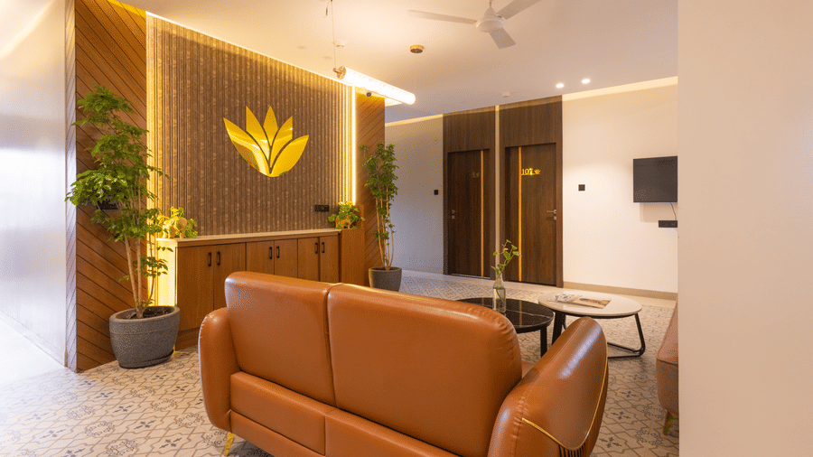 Interior view of the reception and lobby area with a seating arrangement and decorative logo at Pravasa Stay Luv Kush, Indore.