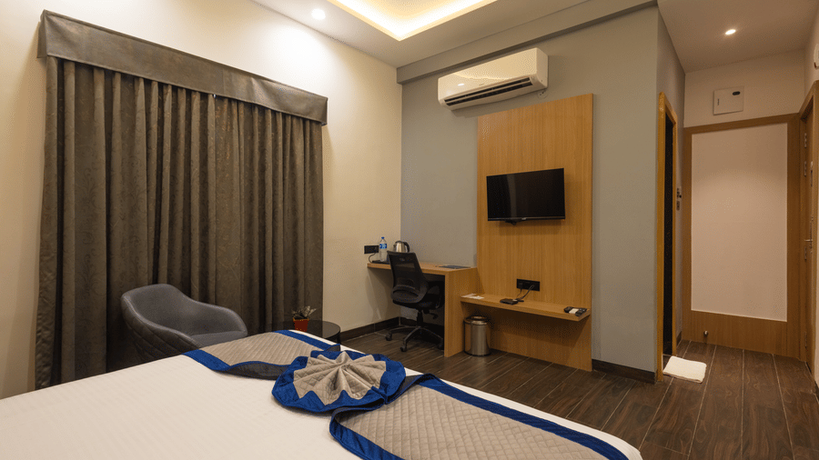 Interior view of a guest room with a bed and a television on the wall at Pravasa Stay Luv Kush, Indore.