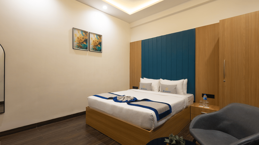 Interior view of a guest room showing the bed, blue headboard, and wooden cabinet at Pravasa Stay Luv Kush, Indore.