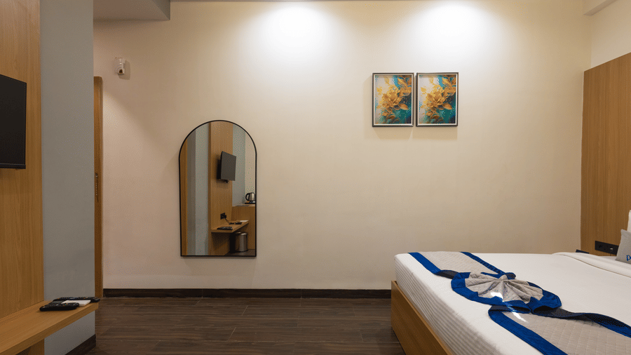 Interior of a guest room showing the bed, mirror, and wall art at Pravasa Stay Luv Kush, Indore.