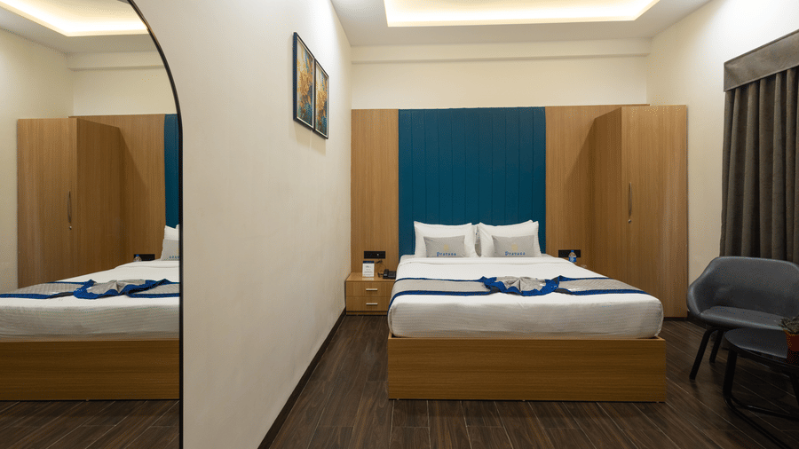 Interior view of a guest room showing the bed, a rounded mirror, and a chair at Pravasa Stay Luv Kush, Indore.