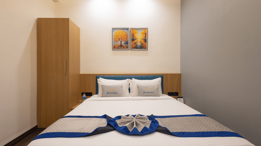 Interior of a guest room showing the bed and a full-length wooden cupboard at Pravasa Stay Luv Kush, Indore.