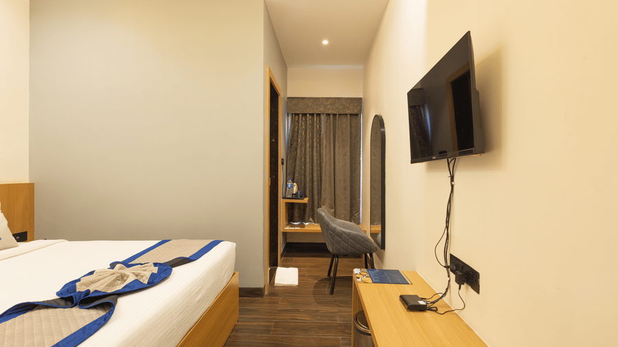 Interior view of a guest room showing the bed, television, and small desk area at Pravasa Stay Luv Kush, Indore.